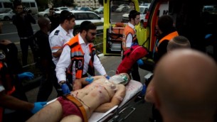 مسعفون إسرائيليون يقومون بنفل منفذ هجوم فلسطيني بعد قيامه بطعن شخصين بالقرب من محطة القطار الخفبف في تل الذخيرة، القدس. (October 30, 2015. Yonatan Sindel/Flash90)