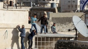 مستوطنون يهود يقفون على سطح مبنى بعد إقتحامهم لمنزلين وسط الخليل، 21 يناير، 2016. (AFP/Hazem Bader)