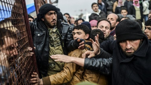 لاجئون فارون من مدينة حلب المحاصرة يتدافعون على الحدود السورية التركية اثناء انتظار الحصول على خيام، 6 فبراير 2016 (Bulent Kilic/AFP)