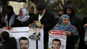 مؤيدون للأسير الفلسطيني المضرب عن الطعام محمد القيق يحملون صورا له خلال تظاهرة تضامنية معه خارج مكاتب اللجنة الدولية للصليب الأحمر بالقرب من مدينة رام الله بالضفة الغربية، 7 فبراير، 2016. (AFP/Abbas Momani)