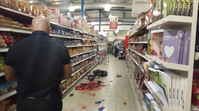 شرطي اسرائيلي ييجل الادلة في ساحة هجوم طعن داخل متجر في مستوطنة في الضفة الغربية، 18 فبراير 2016 (Israel Police)