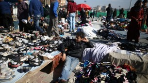 شاب فلسطيني يجلس بين الملابس المستخدمة في سوق البالية الاسبوعي في مخيم نصيرات، في مركز قطاع غزة، 29 فبراير 2016 (MOHAMMED ABED / AFP)