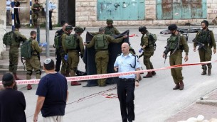 جنود اسرائيليون يغطون جثمان المعتدي الفلسطيني الذي قُتل برصاص جندي اطلق النار على رأسه بينما كان ملقى مصاب على الارض بعد طعنه جندي في الخليل، 24 مارس 2016 (AFP / HAZEM BADER)