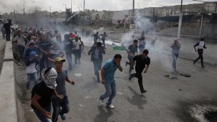 فلسطينيون يفرون من الغاز المسيل للدموع خلال اشتباكات مع قوات امن اسرائيلية في حاجز قلنديا، 6 اكتوبر 2015 (AFP PHOTO/ABBAS MOMANI)