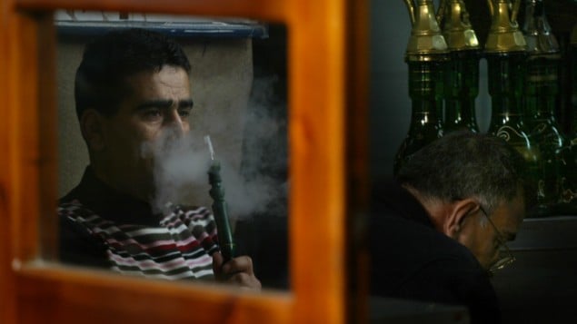 صورة توضيحية لرجل يدخن النرجيلة في مقهى (Michal Fattal/Flash90)