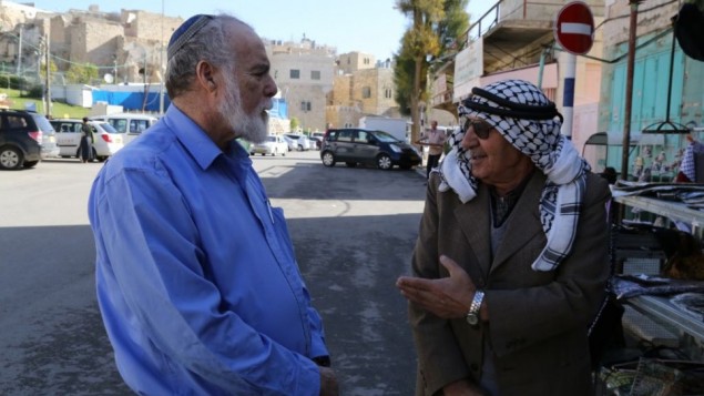 رجلان يهودي وعربي خارج الحرم الإبراهيمي في الخليل، 10 ديسمبر، 2014. (Gershon Elinson/Flash90)