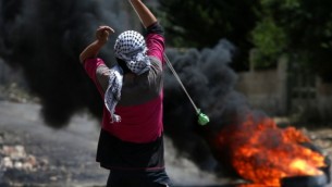 متظاهر فلسطيني يلقي بحجارة مستخدما مقلاعا باتجاه قوات الأمن الإسرائيلية خلال موجهات في 6 مايو، 2016. (AFP PHOTO / JAAFAR ASHTIYEH)
