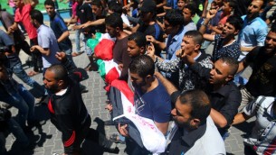 مشيعون فلسطينيون يحملون جثامين الأطفال الثلاثة الذين قُتلوا في حريق تسببت به شمعة، خلال جنازة الأطفال في مخيم الشاطئ بمدينة غزة، السبت، 7 مايو، 2016. (MOHAMMED ABED / AFP)