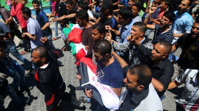 مشيعون فلسطينيون يحملون جثامين الأطفال الثلاثة الذين قُتلوا في حريق تسببت به شمعة، خلال جنازة الأطفال في مخيم الشاطئ بمدينة غزة، السبت، 7 مايو، 2016. (MOHAMMED ABED / AFP)
