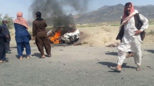 سكان محليون باكستانيون يحتشدون حول مركبة مدمرة تعرضت لهجوم من قبل طائرة بدون طيارة يُتقد بأن زعيم حركة طالبان الأفغانية الملا أختر منصور كان فيها في بلدة أحمد وول النائية في إقليم بلوشيستان، 21 مايو، 2016. (AFP)