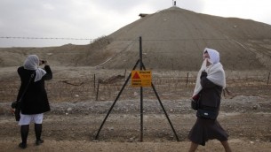 حجاج مسيحيون من الكنيسة الأرثوذكسية اليونانية يجتازون لافتة تحذر من الألغام خلال مشاركتهم في مراسيم عيد الغطاس، في قصر اليهود، في 18 يناير، 2011. (Miriam Alster/Flash90)