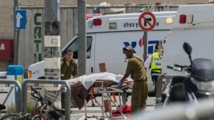 مسعفو الجيش الإسرائيلي يقومون بإخلاء جثة شاب فلسطيني عند حاجز قلنديا بعد محاولة طعن مزعومة، 27 أبريل، 2016. (Yonatan Sindel/Flash90)