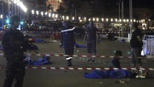 جنود وعناصر شرطة ورجال إطفال يسرون بالقرب من جثث مغطاة بأغطية زرقاء في ’متنزه الإنجليز’ في مدينة نيس التي تقع في الريفييرا الفرنسية في 15 يوليو، 2016 بعد أن قامت شاحنة بدهس جمع من الأشخاص احتشدوا لمشاهدة عرض ألعب نارية. (AFP PHOTO / VALERY HACHE)