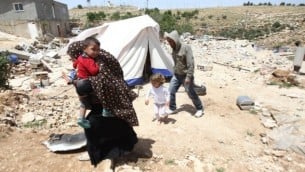 عائلة فلسطينية تم هدم منزلها من قبل جرافات إسرائيلية تمر أمام خيمة في 21 ابريل، 2015 في قرية الديرات جنوبي الضفة الغربية. (Hazem Bader/AFP)