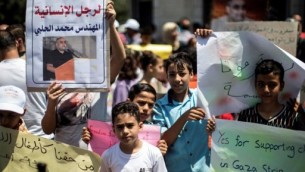أطفال فلسطينيون يحملون صورا لمحمد الحلبي (من اليسار)، مدير فرع ’وورلد فيجين’ في غزة، منظمة غير حكومية مقرها في الولايات المتحدة، خلال احتجاج تضامني معه في مدينة غزة في 7 أغسطس، 2016. (AFP PHOTO / MAHMUD HAMS)