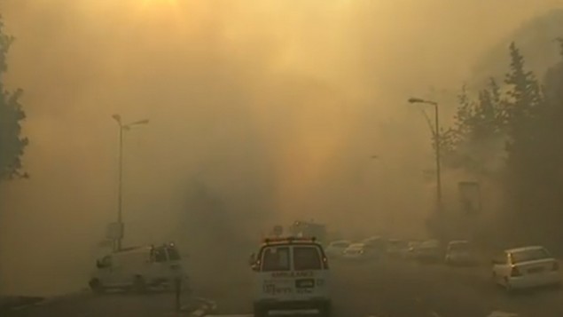 سيارة اسعاف تمر في شوارع حيفا المغطاة في الدخان  بينما يحاول رجال الاطفاء احماد حريق هائل ينتشر في المدينة، 24 نوفمبر 2016 (screen capture: Channel 10)
