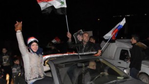 سوريون يلوحون بالاعلام السورية والروسية في شوارع حلب احتفالا بسيطرة قوات النظام السوري على المدينة، 22 ديسمبر 2016 (GEORGE OURFALIAN / AFP)