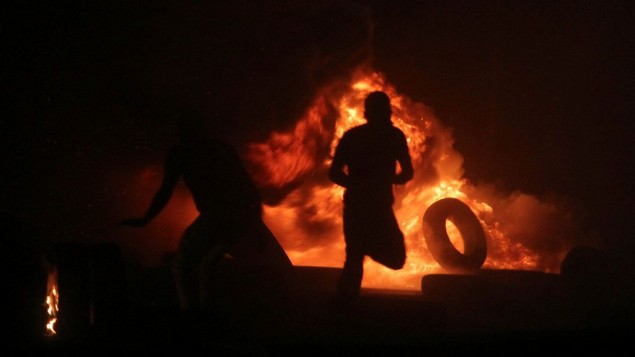 صورة توضيحية: رجال فلسطينيون يقومون بحرق الإطارات خلال مواجهات مع شرطة حرس الحدود الإسرائيلية عند حاجز قلنديا، بين القدس ورام الله، 24 يوليو، 2014. (Issam Rimawi/Flash90) صورة توضيحية: رجال فلسطينيون يقومون بحرق الإطارات خلال مواجهات مع شرطة حرس الحدود الإسرائيلية عند حاجز قلنديا، بين القدس ورام الله، 24 يوليو، 2014. (Issam Rimawi/Flash90)