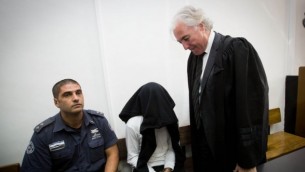 بن ديري (وسط الصورة)، المتهم بقتل شاب فلسطيني يبلغ من العمر 20 عاما من خلال إستخدامه للرصاص الحي خلال مواجهات في بيتونيا في الضفة الغربية، مع محامية تسيون عمير (من اليمين)، خلال جلسة في المحكمة المركزية في القدس، 7 ديسمبر، 2014. (Miriam Alster/Flash90)