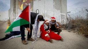 متظاهرين فلسطينيين يرتدون زي بابا نويل خلال مظاهرة ضد الجدار الامني الإسرائيلي في بيت لحم، 23 ديسمبر 2016 (Wisam Hashlamoun/FLASH90)