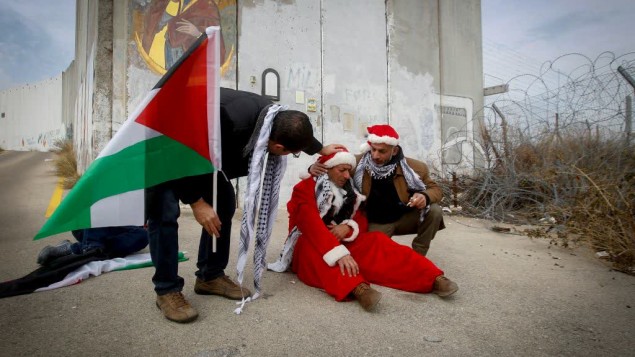متظاهرين فلسطينيين يرتدون زي بابا نويل خلال مظاهرة ضد الجدار الامني الإسرائيلي في بيت لحم، 23 ديسمبر 2016 (Wisam Hashlamoun/FLASH90)