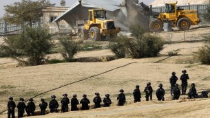 رجال الشرطة يحرسون الجرافات اثناء عمليات الهدم في قرية ام الحيران في النقب في 18 يناير، 2017 AFP PHOTO / MENAHEM KAHANA