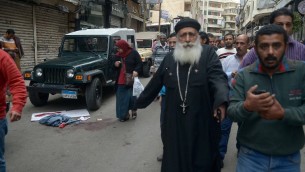 مصريون يمرون امام يقع دم في شارع قريب لكنيسة في الإسكندرية استُهدفت في انفجار خلال احتفال المصلين بأحد الشعانين، 9 أبريل، 2017. (AFP PHOTO / STRINGER)
