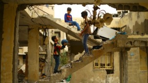 أطفال فلسطينيون يلعبون وسط أنفاض مبنى تم تدميره خلال حرب غزة 2014 في مدينة غزة، 13 أبريل، 2017. (AFP /MOHAMMED ABED)