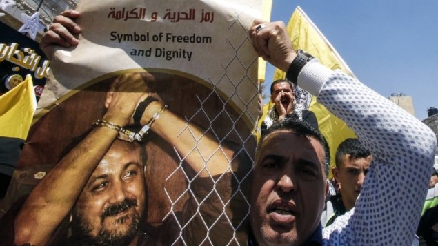 رجل يحمل صورة مروان البرغوثي خلال مظاهرة دعم للاسرى الفلسطينيين المضربين عن الطام في السجون الإسرائيلية، في مدينة الخليل، 17 ابريل 2017 (AFP Photo/Hazem Bader)