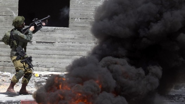 جندي اسرائيلي يطلق قنابل غاز باتجاه متظاهرين فلسطينيين خلال اشتباكات في بلدة دير شرف في الضفة الغربية، غربي نابلس، 22 مايو 2017 (JAAFAR ASHTIYEH / AFP)