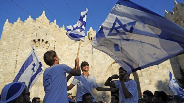 اسرائيليون يلوحون بالاعلام الإسرائيلية في باب العامود، خلال مسيرة احتفال بيوم القدس، في الذكرى الخمسين لتوحيد المدينة بعد حرب 1967، 24 مايو 2017 (AFP PHOTO / Thomas COEX)