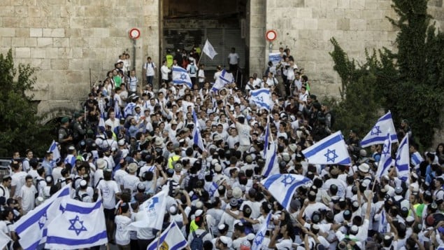 اسرائيليون يلوحون بالاعلام الإسرائيلية في باب العامود، خلال مسيرة احتفال بيوم القدس، في الذكرى الخمسين لتوحيد المدينة بعد حرب 1967، 24 مايو 2017 (AFP PHOTO / Thomas COEX)