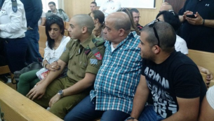 الجندي الإسرائيلي إيلور عزاريا يجلس بين والديه في قاعة المحكمة في مقر الجيش الإسرائيلي في تل أبيب خلال جلسة إستئناف الأربعاء، 3 مايو، 2017. (Judah Ari Gross/Times of Israel)