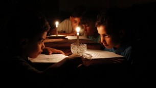 أطفال فلسطينيون في منازلهم يقرؤون الكتب على ضوء الشموع بسبب نقص الكهرباء في مدينة غزة، 13 يونيو / حزيران 2017. (AFP/THOMAS COEX)
