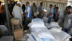 فلسطينيون يتلقون إغاثات في مركز توزيع تابع للأمم المتحدة (الأونروا) في مخيم رفح، جنوب قطاع غزة، 31 يوليو، 2014. (Abed Rahim Khatib/Flash90)