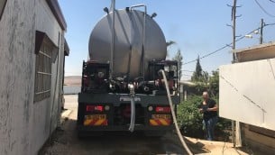 مدير مستوطنة ميغداليم ياعل حشاش ينظر بينما تملأ شاحنة برج المياه في المستوطنة، 4 يونيو 2017 (Jacob Magid/Times of Israel)