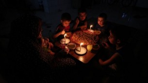 عائلة فلسطينية تتناول وجبة العشاء على ضوء الشموع في منزلهم المرتجل في مخيم رفح، جنوب قطاع غزة، خلال انقطاع للكهرباء، 11 يونيو، 2017. (AFP/SAID KHATIB)