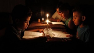 أطفال فلسطينيون في منازلهم يقرؤون الكتب على ضوء الشموع بسبب نقص الكهرباء في مدينة غزة، 13 يونيو / حزيران 2017. (AFP/THOMAS COEX)