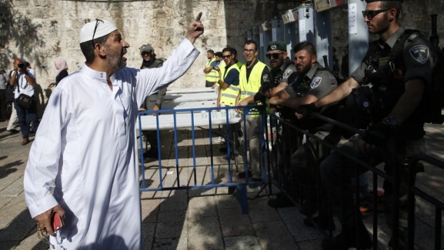 رجل فلسطيني امام حرس حدود اسرائيليين بالقرب من بوابات كشف المعادن عند المدخل الرئيسي للحرم القدسي، 16 يوليو 2017 (AFP PHOTO / AHMAD GHARABLI)