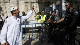 رجل فلسطيني يجادل أفراد من شرطة حرس الحدود بالقرب من البوابات الإلكترونية التي تم وضعها حديثا عن المدخل الرئيسي للمسجد الأقصى في البلدة القديمة في القدس، 16 يوليو، 2017، بعد إعادة فتح الموقع الحساس. (AFP PHOTO / AHMAD GHARABLI)