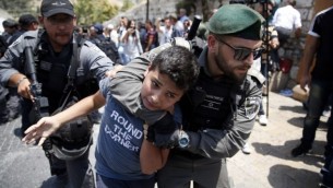 شرطيان من حرس الحدود الإسرائيلي يعتقلان فتى فلسطينيا خلال تظاهرة أمام باب الأسباط في البلدة القديمة في القدس، 17 يوليو، 2017. (AFP/AHMAD GHARABLI)