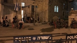 المستوطنون في منزل استولى عليه مستوطنين في الخليل يجلسون خارج المبنى بجوار عناصر حرس الحدود، 26 يوليو 2017 (Jacob Magid)
