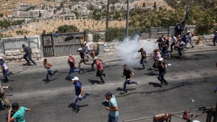 متظاهرون فلسطينيون يهربون من قنابل الغاز المسيل للدوع بعد صلاة الجمعة في حي وادي الجوز في القدس الشرقية، 28 يوليو 2017 (Miriam Alster/Flash90)