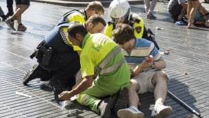 شخص يساعده عناصر شرطة اسبان ورجلان بعد هجوم دهس بشاحنة، ادى الى مقتل 13 شخصا واصابة حوالي 100 شخص في برشلونة، 17 اغسطس 2017 (AFP PHOTO / Nicolas CARVALHO OCHOA)