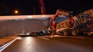 عمال الإنقاذ والشرطة في موقع انهيار جسر مشاة على شاحنة في الطريق السريع رقم 4 بالقرب من غيفعات شموئيل، 14 أغسطس، 2017. (Moti arelitz/Flash90)