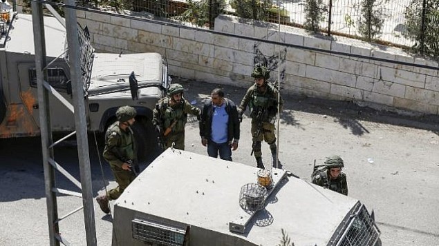 صورة تم التقاطها في 26 سبتمبر، 2017، في قرية بيت سوريك في الضفة الغربية تظهر جنودا إسرائيليين يقومون باعتقال فلسطيني، أشارت تقارير إلى أن شقيقه قام بارتكاب هجوم أسفر عن مقتل ثلاثة إسرائيليين في مستوطنة هار أدار. (AFP PHOTO / ABBAS MOMANI)