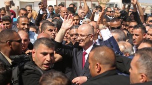 رئيس الحكومة الفلسطيني رام الحمد الله (وسط الصورة) محاط برجال الأمن عند وصوله إلى معبر إيريز الحدودي في بيت حانون شمال قطاع غزة، 2 أكتوبر، 2017، في زيارة أولى إلى القطاع لإجراء محادثات تهدف إلى التوصل إلى اتفاق مصالحة بين حركتي فتح وحماس. (AFP PHOTO / MAHMUD HAMS)