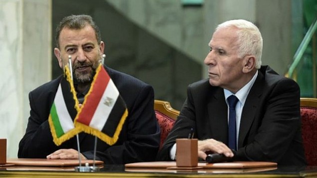 المسؤول في حركة ’فتح’ عزام الأحمد، من اليمين، والمسؤول في ’حماس’ صالح العاروري، من اليسار، يتحدثان للصحافيين بعد التوقيع على اتفاق مصالحة في القاهرة، 12 أكتوبر، 2017. (AFP/Khaled Desouki)