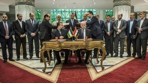 نائب رئيس المكتب السياسي الجديد لحركة ’حماس’ صالح العاروري (الجالس من اليسار) والمسؤول في حركة ’فتح’ أحمد العزام (الجالس من اليمين) يوقعان على اتفاق المصالحة في القاهرة، 12 أكتوبر، 2017. AFP) Photo/Khaled Desouki)