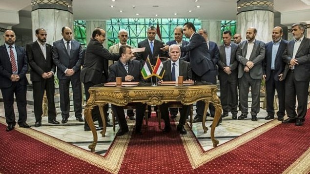 نائب رئيس المكتب السياسي الجديد لحركة ’حماس’ صالح العاروري (الجالس من اليسار) والمسؤول في حركة ’فتح’ أحمد العزام (الجالس من اليمين) يوقعان على اتفاق المصالحة في القاهرة، 12 أكتوبر، 2017. AFP) Photo/Khaled Desouki)